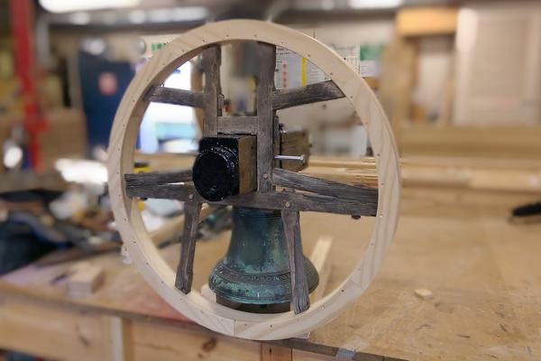 Photo of a bell and yoke being restored in a joinery workshop