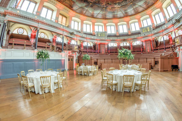 Photo of the Sheldonian Theatre interior set up for a formal dinner, with chairs around round tables