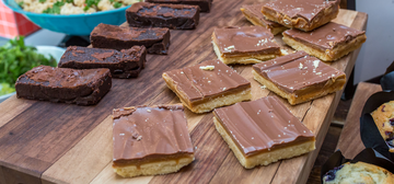 Photo of millionaire shortbread and chocolate brownies on a wooden board