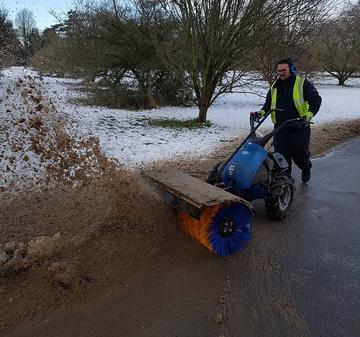 Photo of a man wearing a high-vis jacket and earmuffs using a snow-plough in the Parks